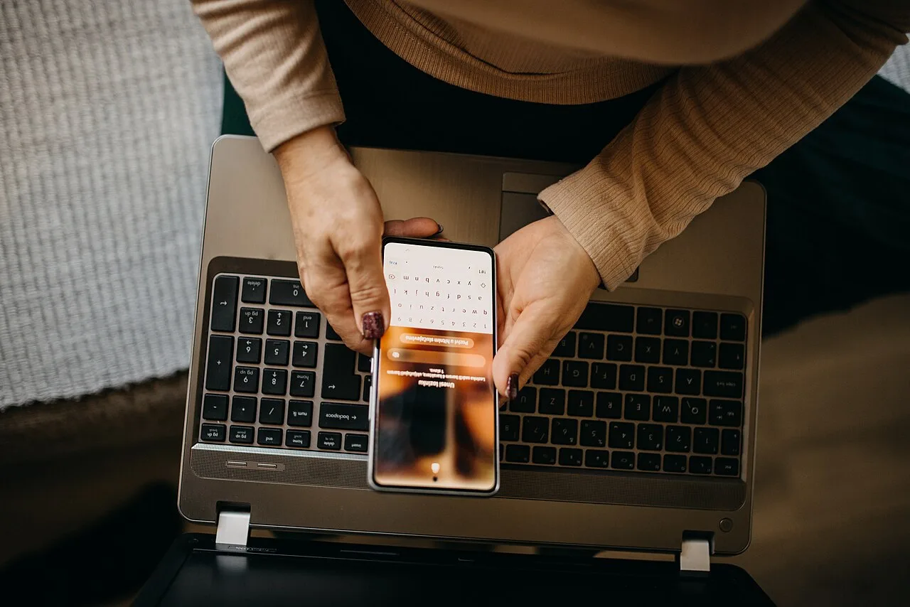 Mature woman comparing online choices on a laptop and phone