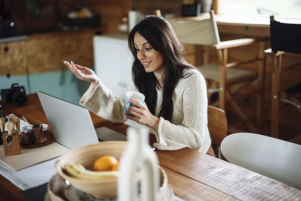 Adult woman talking beside an open laptop